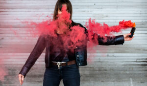 eine Frau, aus deren Gesicht roter Rauch aufsteigt